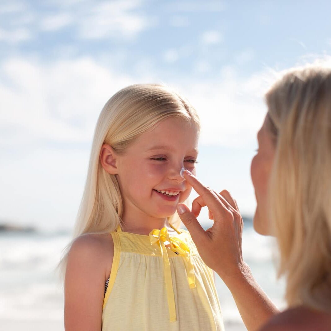 Mother applying sunscreen to daughter - Skincare Tips